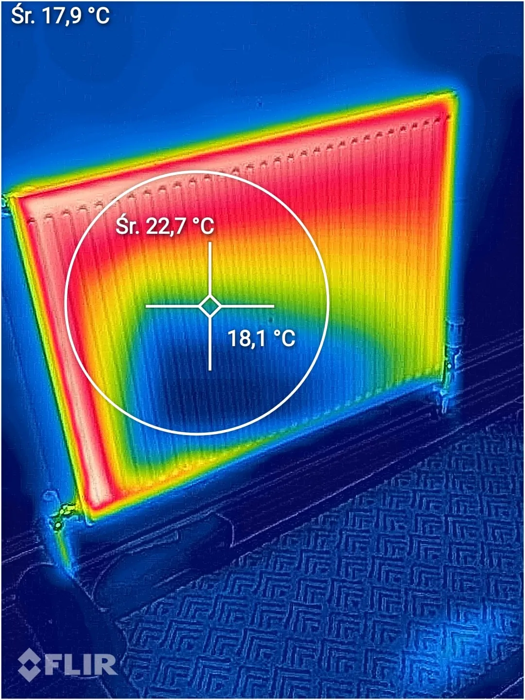 Thermal camera image of a radiator: the top and sides show hot, with a cooler area across the lower middle and spot readings of 22.7 and 18.1 degrees